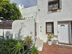 un bâtiment blanc avec une porte blanche et quelques plantes dans l'établissement Placa EIVISSA,1, à Empuriabrava