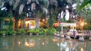 una casa sull'acqua con una barca davanti di สวนผึ้ง2 รีสอร์ท - Suan Phueng 2 Resort a Bang Sare
