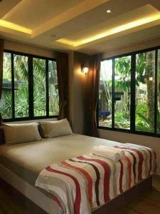 een groot bed in een kamer met grote ramen bij สวนผึ้ง2 รีสอร์ท - Suan Phueng 2 Resort in Bang Sare