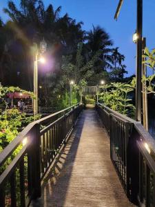 un puente de madera con luces encendidas por la noche en สวนผึ้ง2 รีสอร์ท - Suan Phueng 2 Resort en Bang Sare