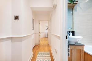 a bathroom with white walls and a sink and a tub at Welcome London Theatreland in London