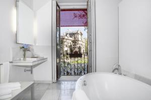 a white bathroom with a tub and a window at Hospes Puerta de Alcalá, a Member of Design Hotels in Madrid