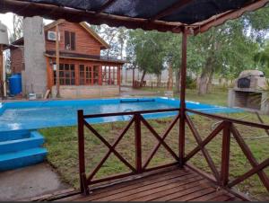 a pool with a wooden deck and a house at Dino's Ranch in Villa El Chocón