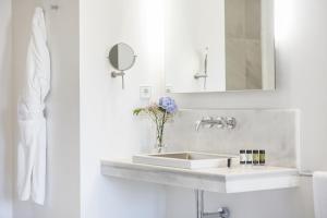 a white bathroom with a sink and a mirror at Hospes Puerta de Alcalá, a Member of Design Hotels in Madrid
