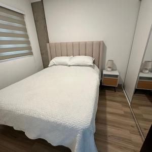 1 dormitorio con 1 cama grande con sábanas blancas en Departamento en la playa Mar Adentro para 4 personas en Santa Cruz de la Sierra