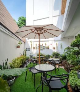 曼谷的住宿－ZEN MASTER HOTEL，一个带桌椅和遮阳伞的庭院