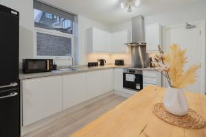 a kitchen with white cabinets and a vase on a wooden table at 2 Bed Garden Flat at Primal Estates Short Lets in Brighton in Brighton & Hove