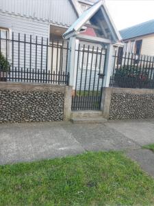 a fence in front of a house with a driveway at Cabaña Los Alpes in Curacautín