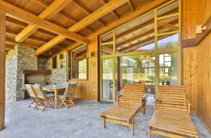 eine Terrasse mit einem Tisch, Stühlen und einem Kamin in der Unterkunft Luxury Chalets Pirin Golf & Country Club in Bansko