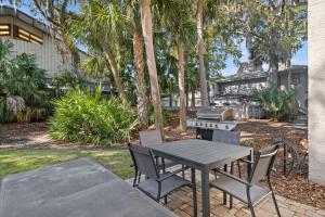 una mesa de picnic y sillas con una parrilla y palmeras en Island House 131, en Hilton Head Island