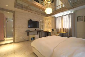 a bedroom with a large white bed and a flat screen tv at Songdo February Hotel Amnam in Busan