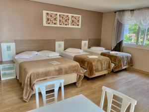 Una habitación de hotel con dos camas y una mesa y sillas. en Pousada Vovô Nino, en Gramado