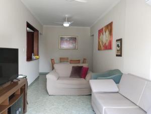 Il comprend un salon doté d'un canapé blanc et d'une télévision à écran plat. dans l'établissement Apartamento no canto do forte, à Praia Grande
