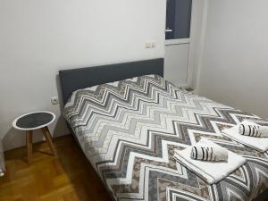 a bedroom with a bed with a comforter and a stool at Penthouse in Užice +12 photos