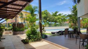 an outdoor patio with a pool and tables and chairs at Pousada Novo Prado in Prado