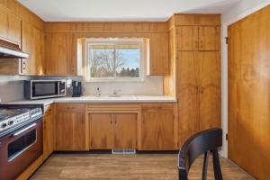 a kitchen with wooden cabinets and a sink and a window at Massillon Vacation Rental with On-Site Pond Access! in Massillon