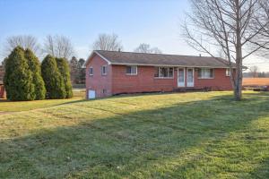 a red brick house with a tree in the yard at Massillon Vacation Rental with On-Site Pond Access! in Massillon