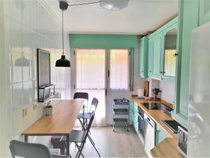 une cuisine avec des armoires vertes, une table et des chaises dans l'établissement Logrocity Puerta del Ebro Parking privado gratis, à Logroño