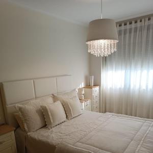 Un dormitorio con una gran cama blanca con una lámpara de araña. en Beiramar, en Cedeira
