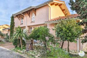 une maison rose avec des arbres devant elle dans l'établissement Biscarrosse Duplex classé 2 étoiles avec parking privatif pour 6 personnes, à Biscarrosse