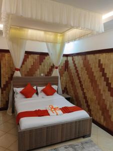 a bedroom with a large bed with red pillows at Hotel Double N - Kisumu in Kisumu