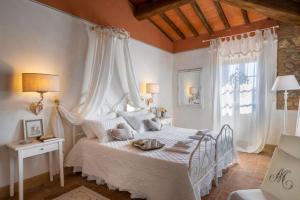 a bedroom with a white bed with curtains and a window at La Mandriola in Lajatico