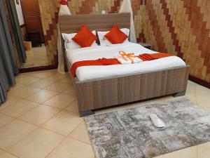 een slaapkamer met een bed met oranje kussens bij Hotel Double N - Kisumu in Kisumu