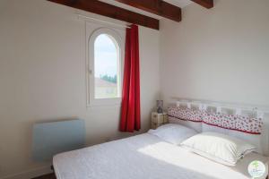 a bedroom with a bed with a red curtain and a window at Biscarrosse Bourg Appartement avec terrasse classé 1 étoile pour 4 personnes in Biscarrosse
