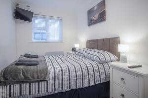 Castle Cove - 1 Bedroom Apartment - Tenby في تينبي: غرفة نوم بيضاء بها سرير ونافذة