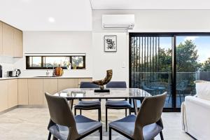 Urban Oasis in Heart of Homebush في سيدني: مطبخ وغرفة طعام مع طاولة وكراسي زجاجية