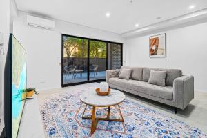 a living room with a couch and a table at Urban Oasis in Heart of Homebush in Sydney