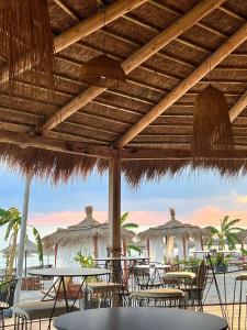 restauracja ze stołami, krzesłami i słomianymi parasolami w obiekcie Domi Beach Valley w mieście Dhërmi
