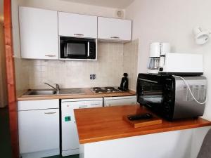 eine Küche mit weißen Schränken und einer Mikrowelle in der Unterkunft Appartement Saint-François-Longchamp, 2 pièces, 6 personnes - FR-1-635-109 in Saint-François-Longchamp