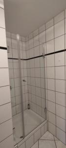 a bathroom with a shower with white tile walls at Ferienwohnung Am Weilsberg in Lindlar