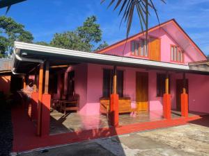 una casa rosa con una panchina davanti di Casa Nativo Spring Arenal a Fortuna