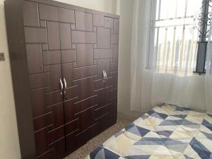 Schlafzimmer mit einem Kopfteil aus Holz und einem Bett in der Unterkunft Bright & Beautiful 2-Bed Apartment, Central Kumasi in Kumasi