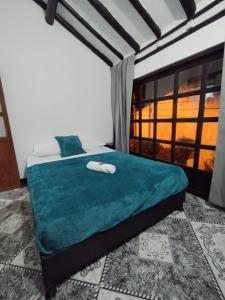 Bett in einem Zimmer mit einem großen Fenster in der Unterkunft Hospedaje Casa Versalles in Villa de Leyva