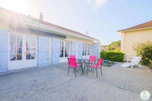 a patio with pink chairs and a table in front of a house at Sanguinet Charmante maison avec jardin pour 6 personnes in Sanguinet +19 photos
