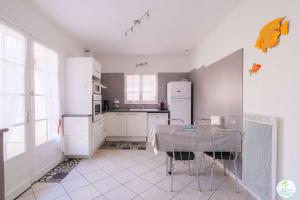 a kitchen with white appliances and a table with chairs at Sanguinet Charmante maison avec jardin pour 6 personnes in Sanguinet