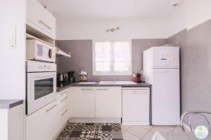 a white kitchen with a sink and a refrigerator at Sanguinet Charmante maison avec jardin pour 6 personnes in Sanguinet