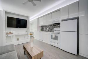 a kitchen with white cabinets and a tv and a table at KCM Tremont Oaks Apartments 5 in Cleveland