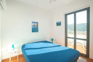 a bedroom with a blue bed and a large window at Giglio Blu 1 in Campese