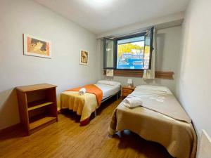 Habitación pequeña con 2 camas y ventana en Apartamentos Candanchu 3000, en Candanchú