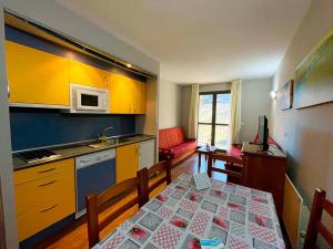 a kitchen with a table and a kitchen with yellow cabinets at Apartamentos Candanchu 3000 in Candanchú