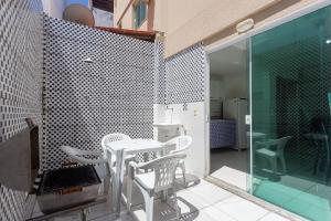 een patio met witte stoelen, een tafel en een glazen deur bij Sobrado a 300m da praia de Ilhéus VCM005 in Ilhéus