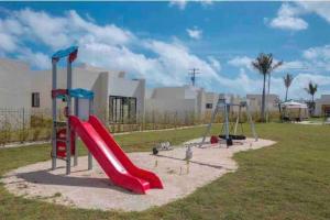 un parque infantil con un tobogán rojo y columpios en Downtown Punta Cana luxuryVilla, en Punta Cana