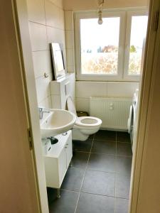 a bathroom with a toilet and a sink and a window at DEOSAI Apartment Kelkheim in Kelkheim