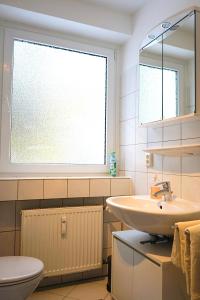 a bathroom with a sink and a toilet and a window at Kompaktes Apartment in ruhiger Lage in Wolfsburg