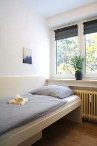 a bed in a bedroom with two windows at Kompaktes Apartment in ruhiger Lage in Wolfsburg
