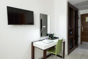 a room with a desk with a tv and a green chair at Ibis Styles Accra Airport in Accra